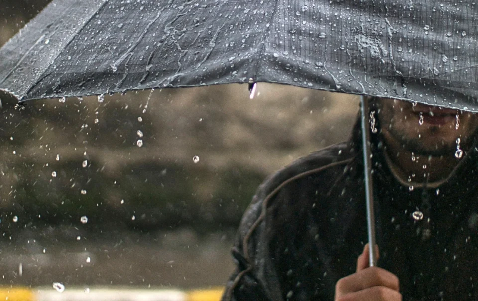 Man holding an umbrella in Kota Kinabalu during a downpour