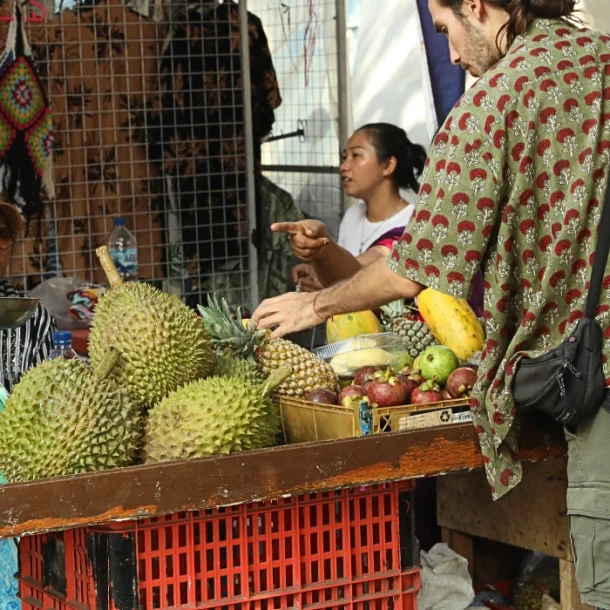 A tourist selecting fresh fruits at the bustling Gaya Street Market in Kota Kinabalu, Sabah.