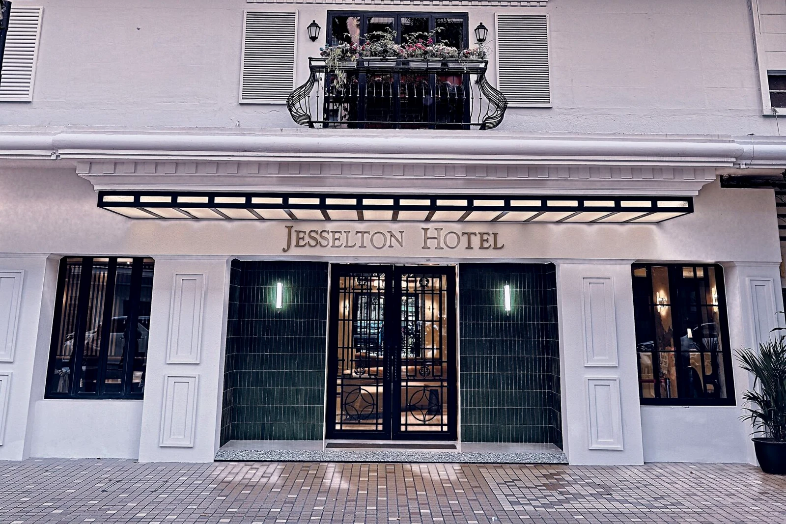 The heritage facade of The Jesselton Hotel on Gaya Street — Juliet balcony, illuminated canopy and brass JESSELTON HOTEL lettering above the emerald-tiled entrance